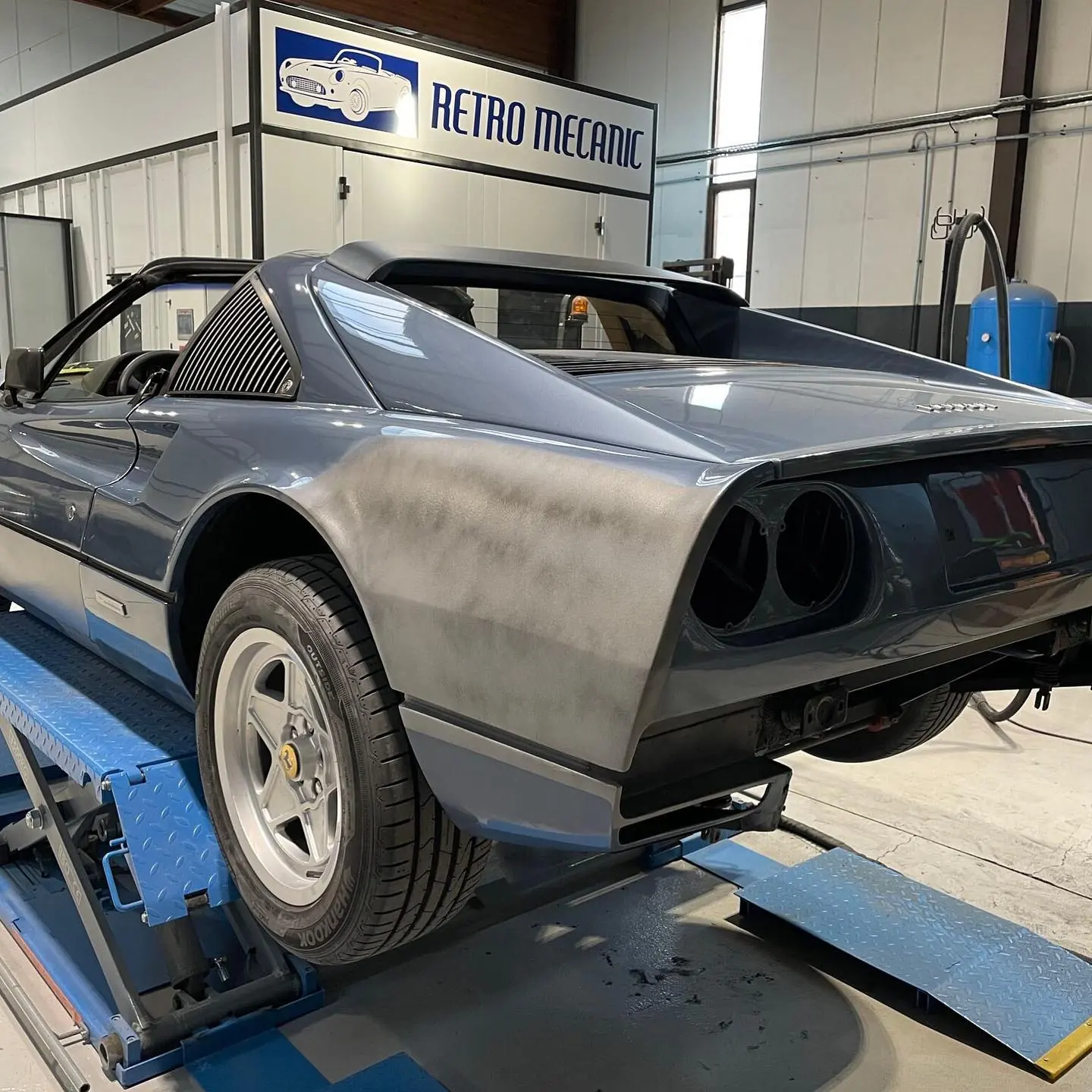 Aile arrière de Ferrari 308 GTS poncée jusqu'à la tôle, en préparation avant peinture, sur pont à ciseaux