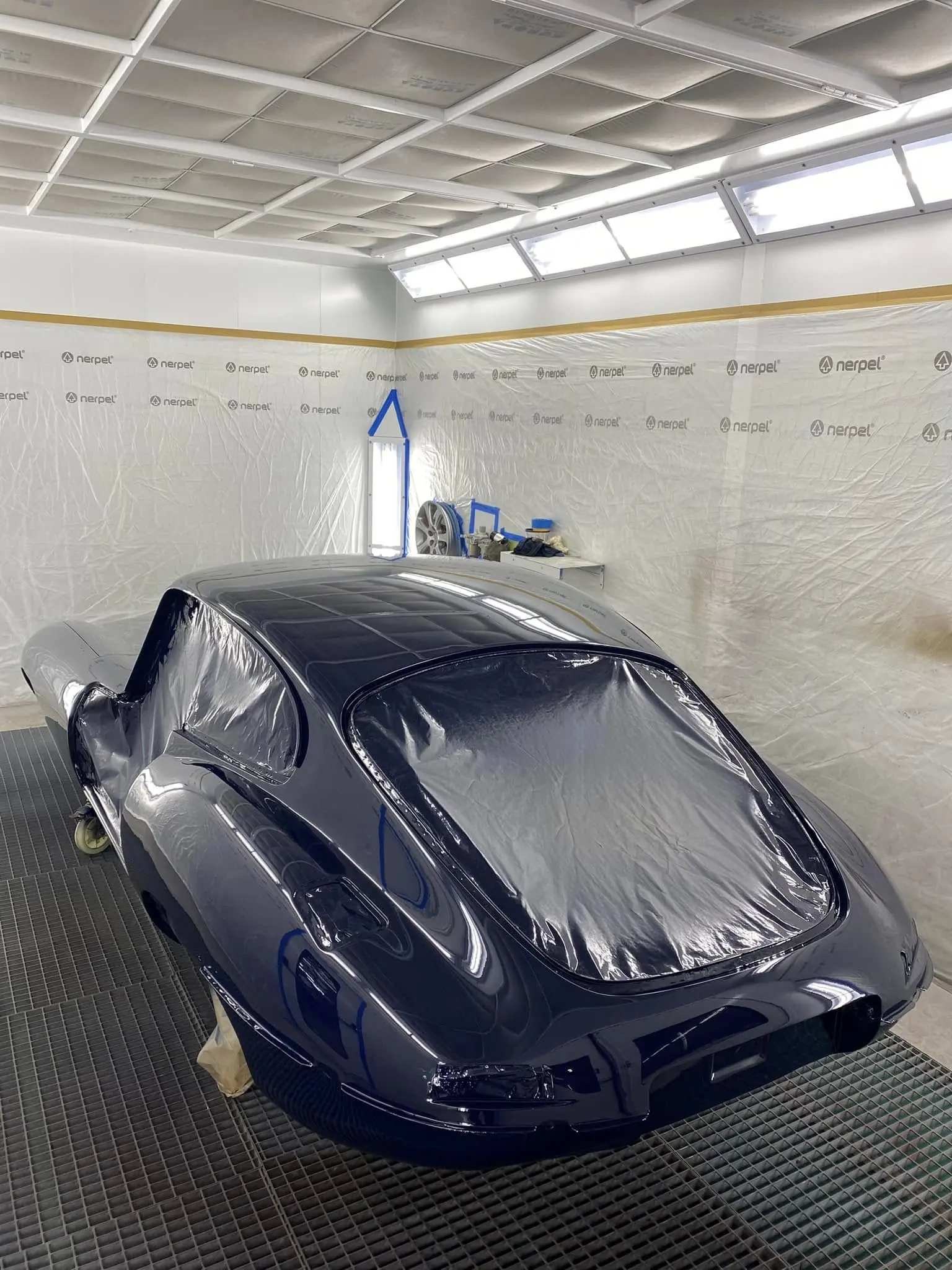 Arrière d'une Jaguar Type E peinte en bleu foncé dans la cabine de peinture