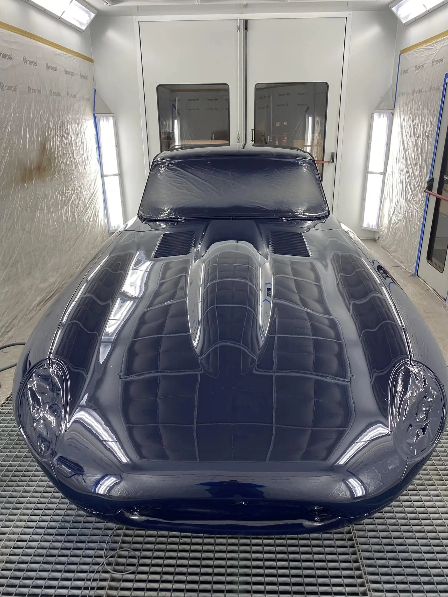 Jaguar Type E fraîchement peinte en bleu foncé dans la cabine de peinture, vue de face