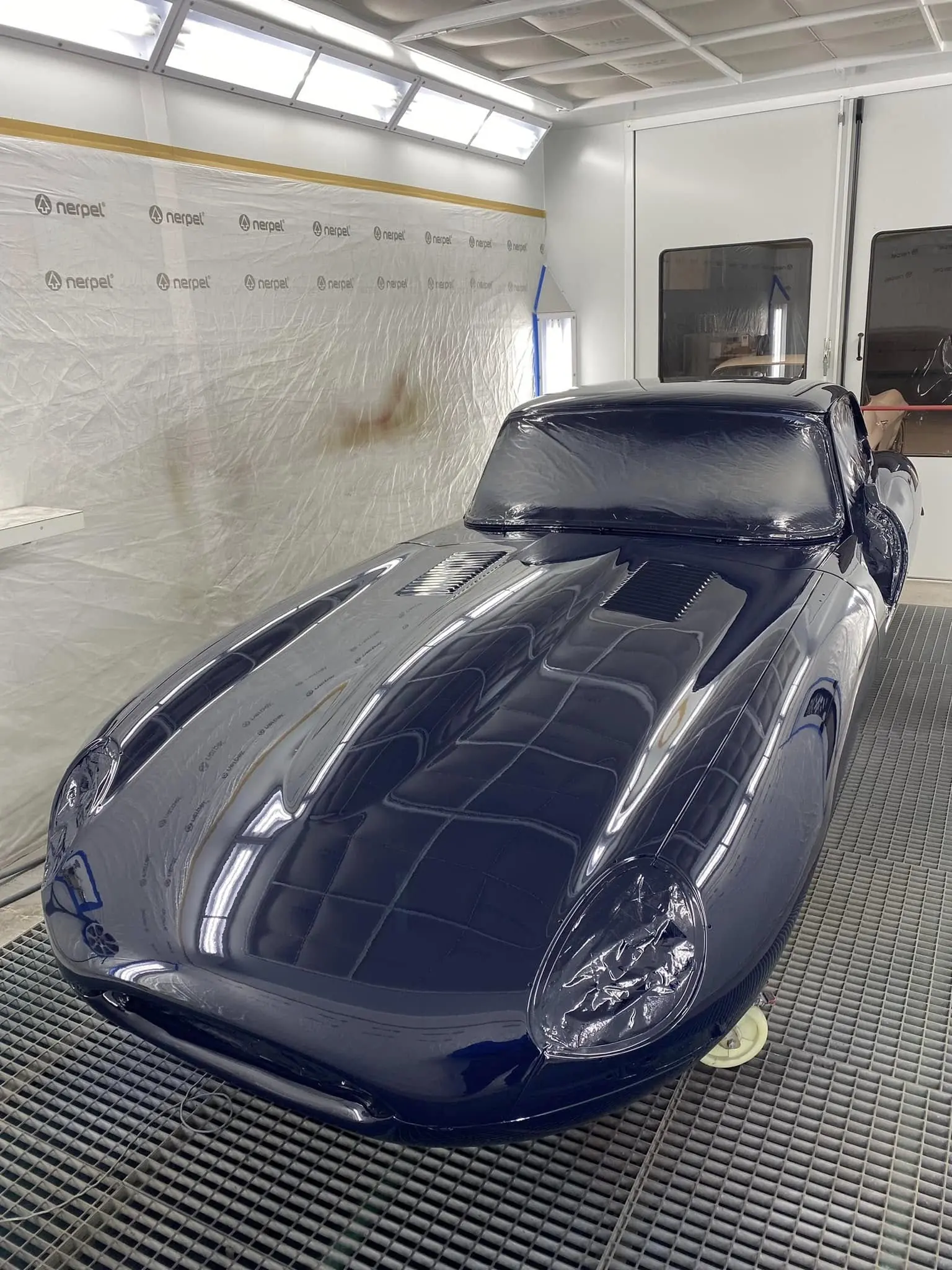 Jaguar Type E en bleu foncé brillant dans la cabine de peinture, vue trois quarts avant