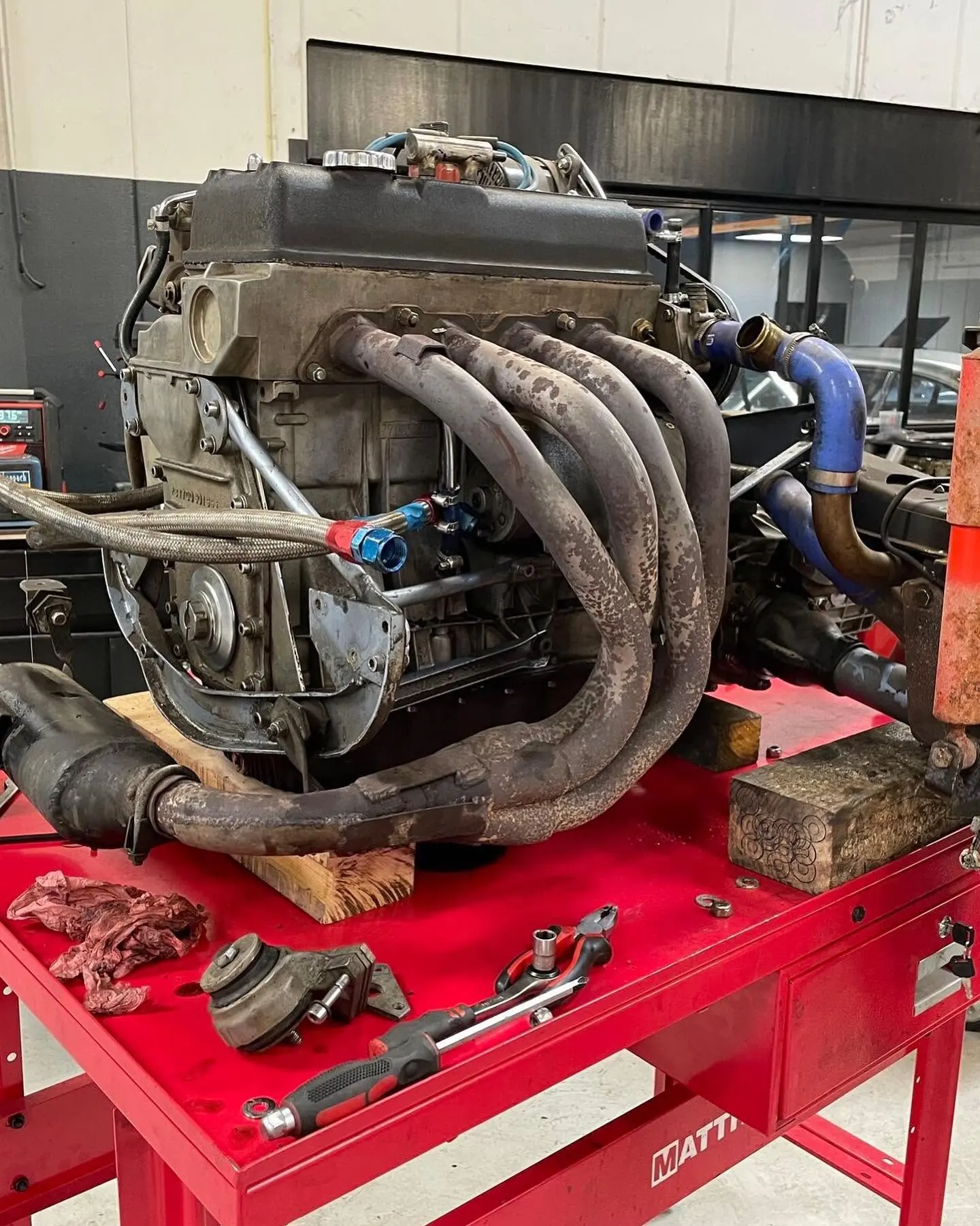 Moteur de voiture de collection déposé sur un établi, avec son échappement, pendant une réfection